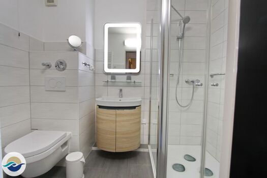 Ein modernes Badezimmer ist mit einem Handtuchheizkörper, einem Waschtisch mit Stauraum für Ihre Kosmetika und Spiegelschrank ausgestattet.