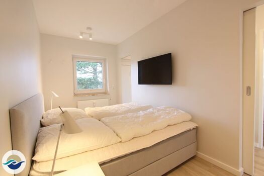 Das Schlafzimmer ist mit einem Boxspringbett (180 x 200 cm), einem Kleiderschrank und einem wandhängenden TV ausgestattet.