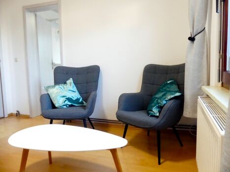 Wohnzimmer mit zwei Ohrensesseln und SAT TV