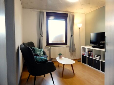 Wohnzimmer mit zwei Ohrensesseln und SAT TV