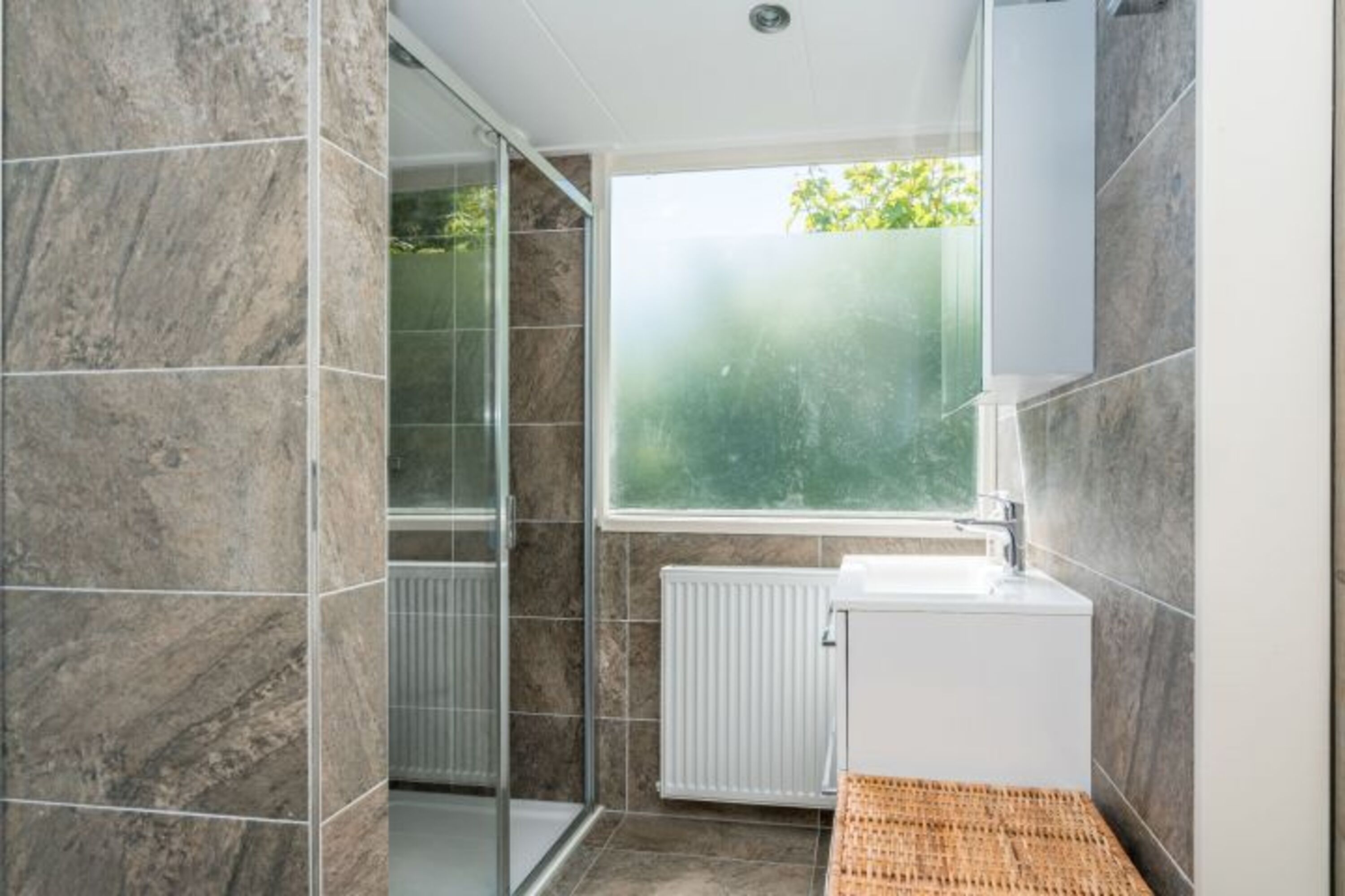 Das moderne, neue Badezimmer mit Dusche und Waschbecken