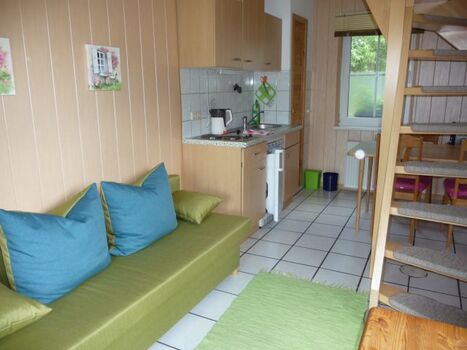 der Eingangsbereich mit Schlafsofa und SAT-TV und Küchenzeile mit Esstisch