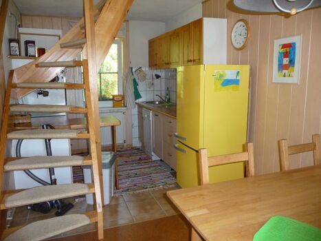 Blick vom Essbereich in den Küchenbereich mit Geschirrspüler, komfortable Treppe ins Obergeschoss zu Schlafbereich un Bad