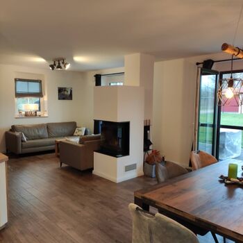 Gemütlicher Wohnbereich mit Kamin und bodentiefen Fenstern