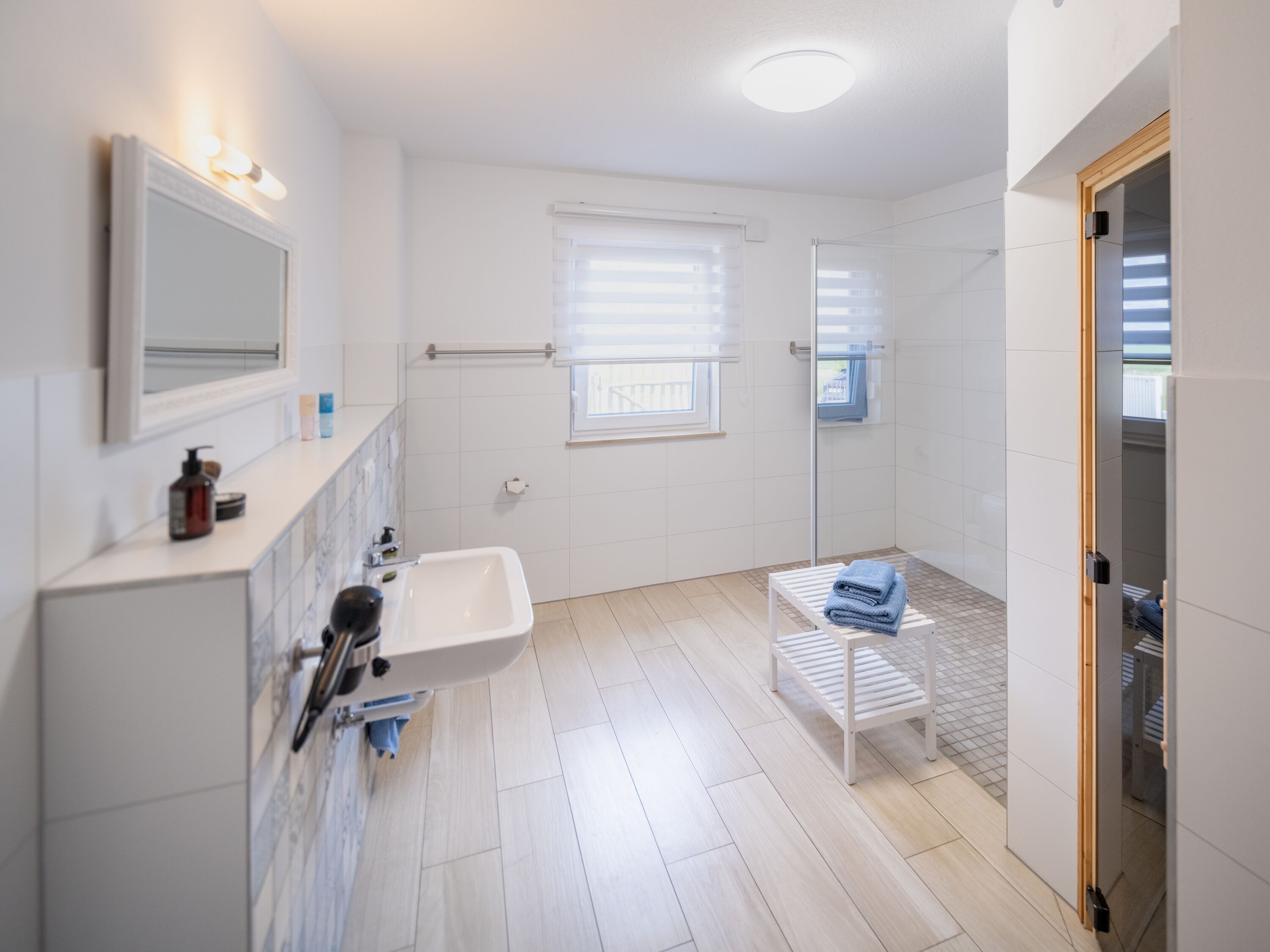 Bad 1 im EG: Waschbecken, Fön, Dusche, Sauna, Toilette, Spiegel, Rolladen, Fliegengitter.