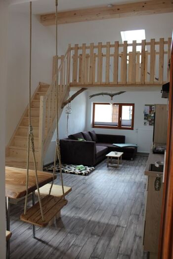 Der geräumige, helle Wohnraum mit Schaukel am Esstisch und Aufgang zur Galerie
