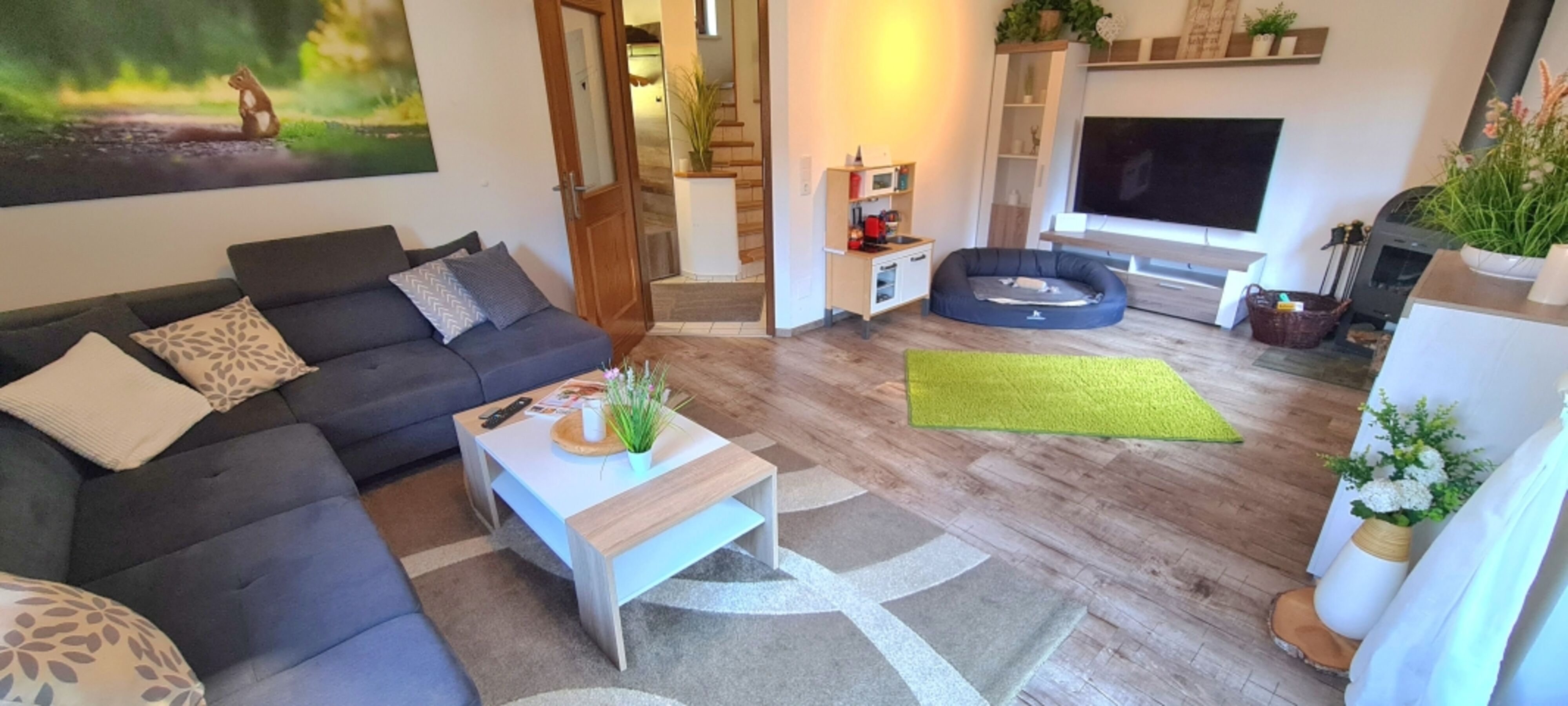 Wohnzimmer mit L-Lounge Couch // 55 Zoll Smart TV // Kaminofen // große Terrassentür zum Garten // TOP WLAN