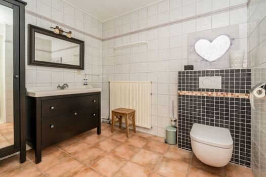 Das Badezimmer mit Dusche, Badmöbel und Toilette