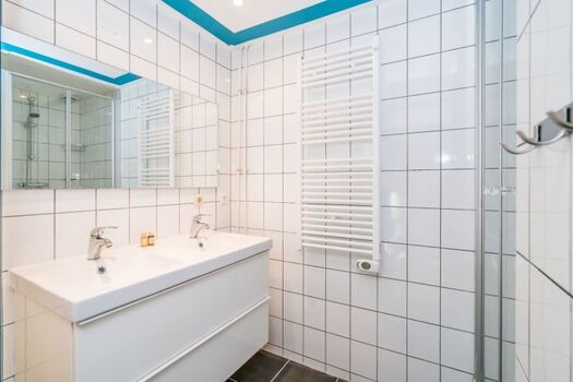 Das Bad mit Dusche und einem doppelten Waschbecken