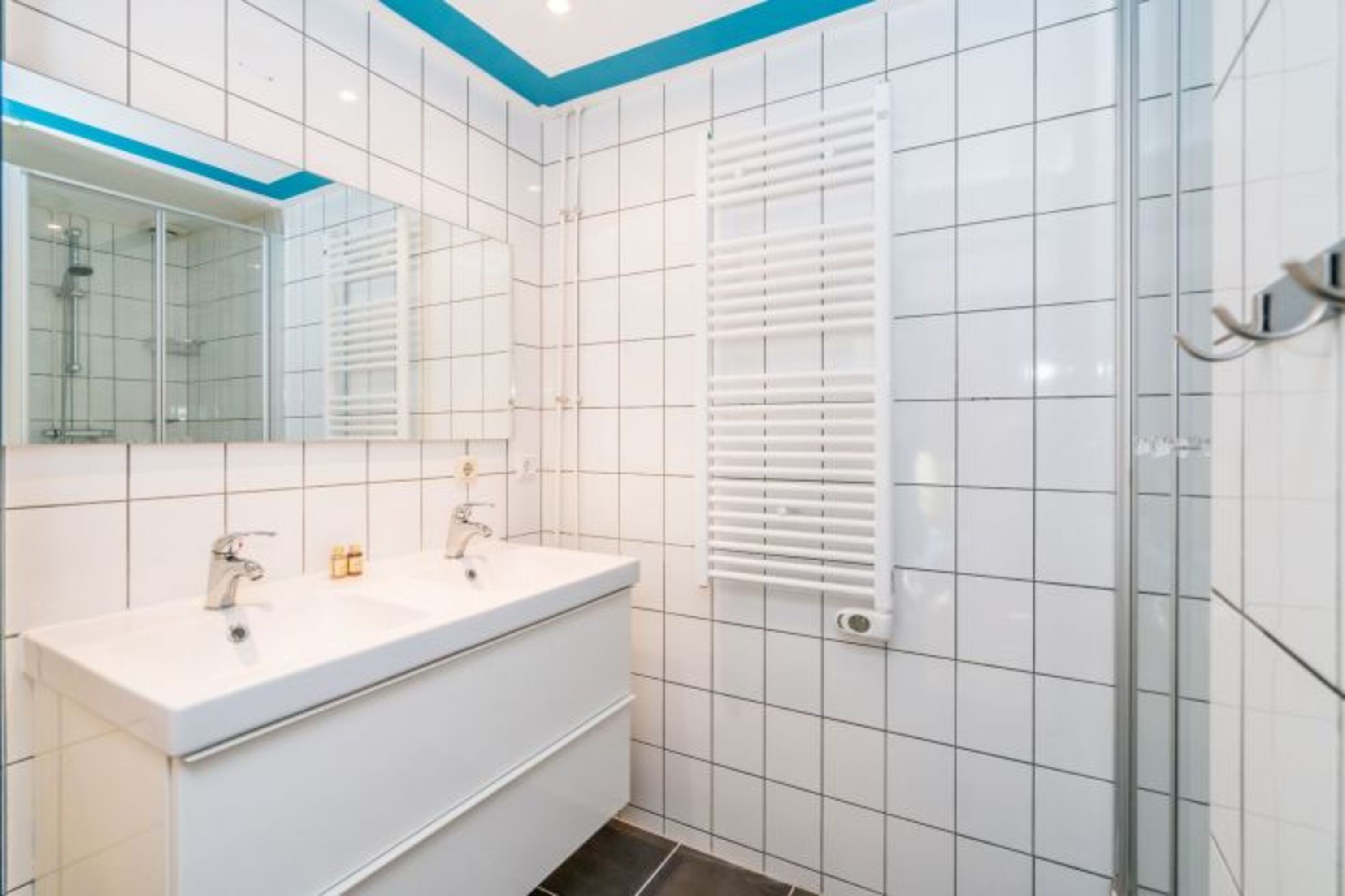 Das Bad mit Dusche und einem doppelten Waschbecken