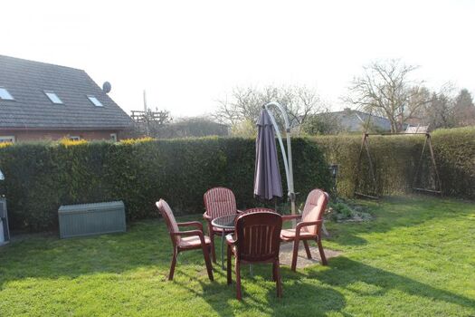 Gartenstühle, Tisch und Sonnenschirm vor dem Bungalow