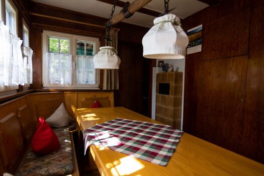 Der Aufenthaltsraum mit großem Esstisch und Kachelofen