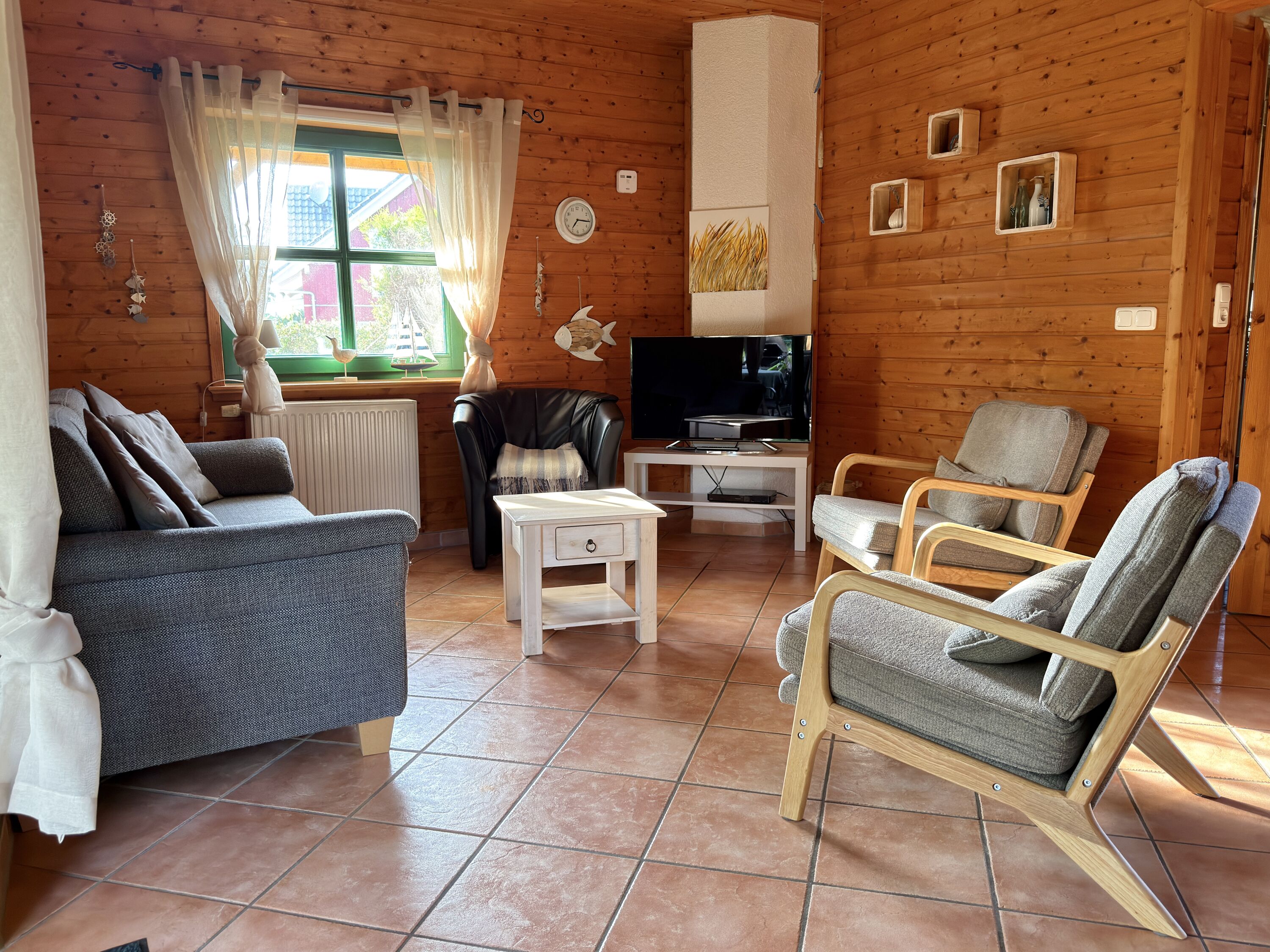 Wohnzimmer mit Couch, Sesseln und Smart-TV
