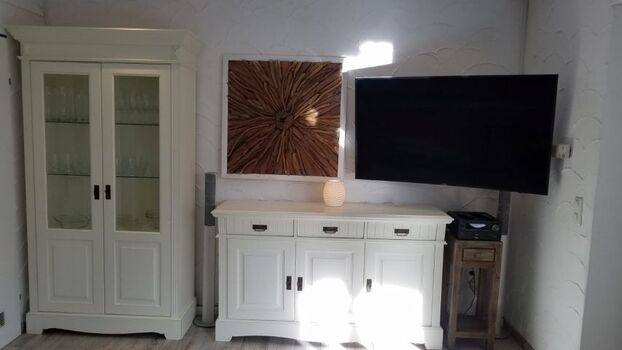 Vitrine gefüllt mit Gläsern, Sideboard und Smart TV mit Netflix