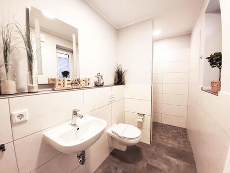 Duschbad mit Erdgeschoss mit bodengleichem Duschbereich, WC, Waschbecken und zwei Fenster