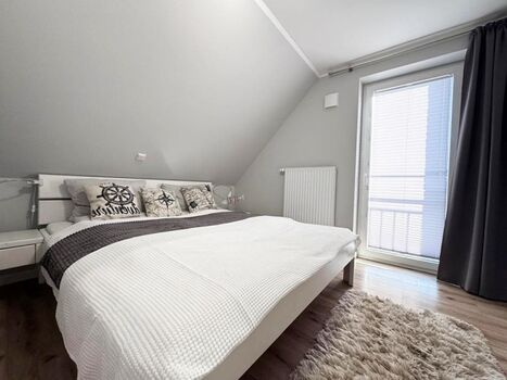 2. Schlafzimmer mit Doppelbett, Kleiderschrank, TV, Ganzkörperspiegel und bodentiefem Fenster