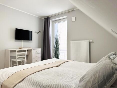 1. Schlafzimmer mit Doppelbett, Kleiderschrank, TV, Ganzkörperspiegel und bodentiefem Fenster