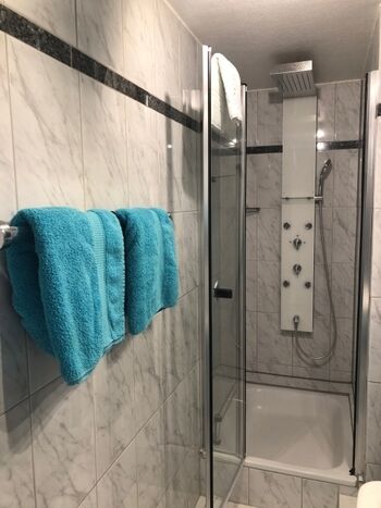 Komfortables Marmor-Badezimmer mit tropischer Regendusche und Massagedüsen....