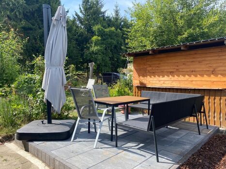 Gemütliche Terrasse im Garten mit Sitzlounge und Sonnenschirm, ideal für entspannte Stunden.
