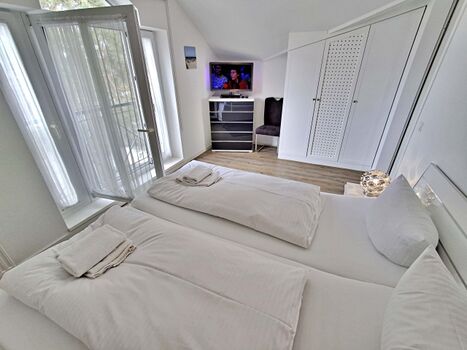 Schlafzimmer mit Doppelbett und zusätzlichem Flachbild-TV