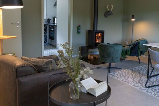 Ein Kamin als Herzstück, großzügiger Esstisch und bequeme Sessel – Momente voller Wärme und Gemütlichkeit.