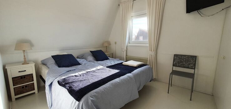 Schlafzimmer mit Doppelbett und TV