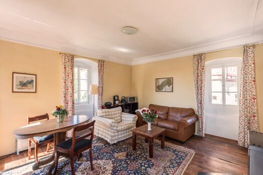 Das gemütliche Wohnzimmer mit Esstisch, Sofaecke und Kaminofen