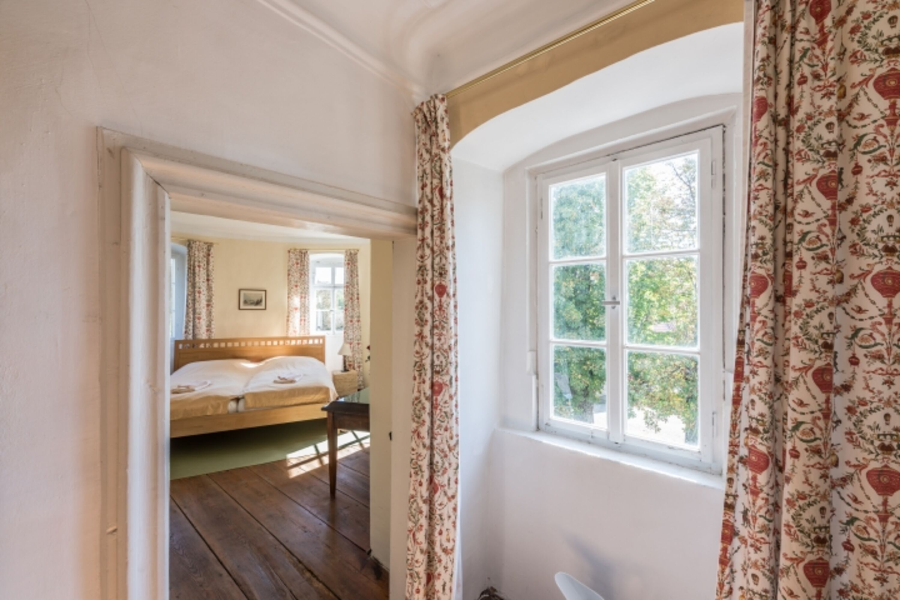 Blick aus dem Wohnzimmer mit geschmackvollen Vorhängen ins Schlafzimmer