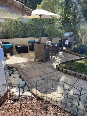 Terrasse eingezäunt mit Loungemöbel, Esstisch, Gasgrill und Kräuterspirale