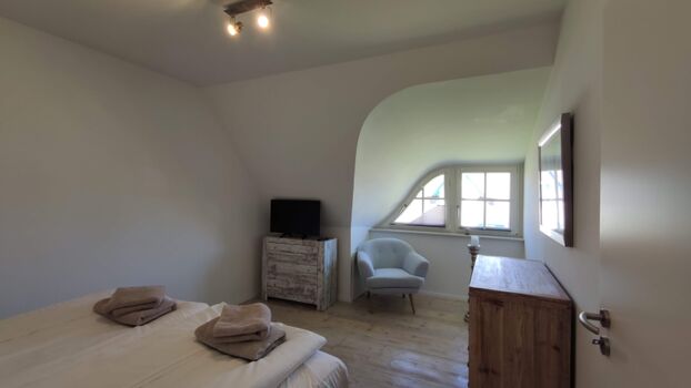 Schlafzimmer 1 mit zwei Kommoden, Sessel und TV