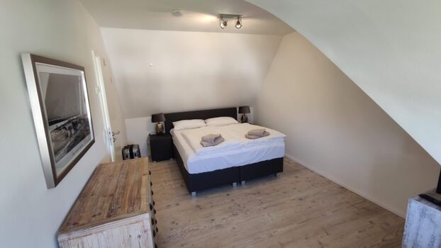 Schlafzimmer 1 mit zwei Kommoden, Sessel und TV