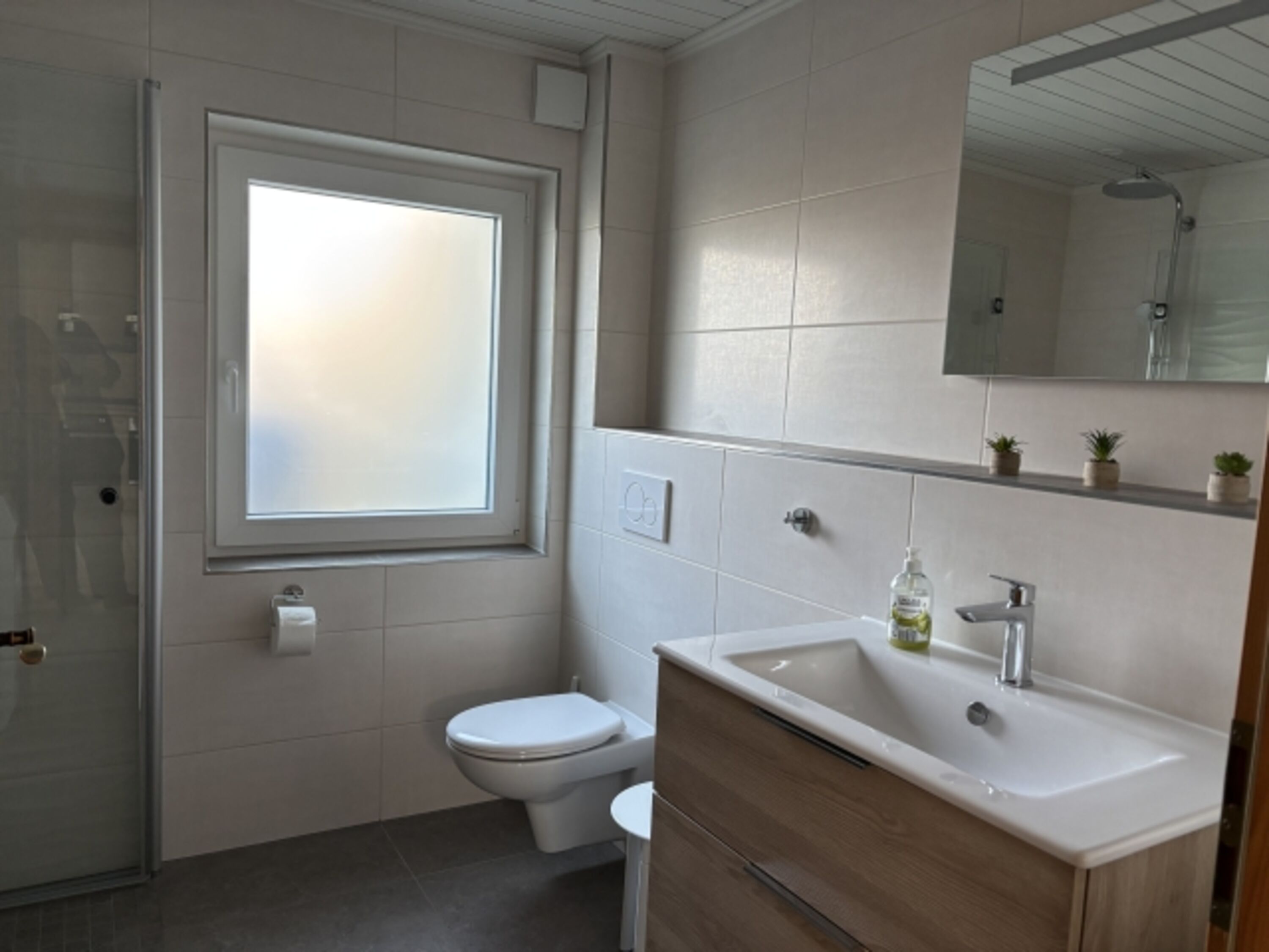 Modernes Bad mit Waschmaschine und Regendusche