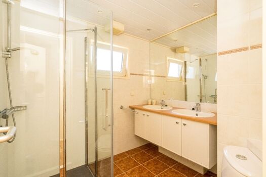 Badezimmer mit Toilette, Dusche und Doppelwaschbecken