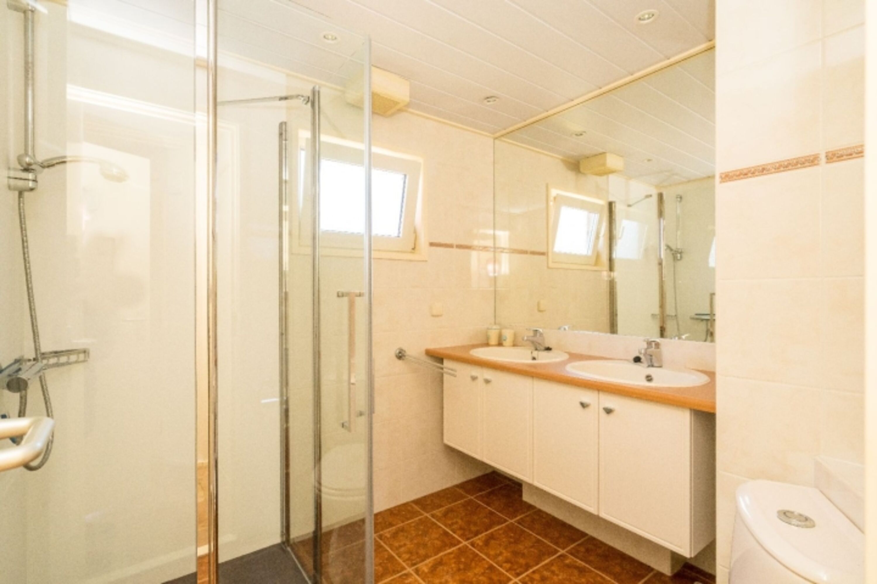 Badezimmer mit Toilette, Dusche und Doppelwaschbecken