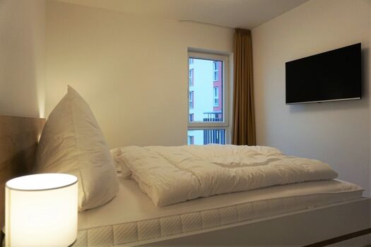 Schlafzimmer mit Fernseher und Kleiderschrank