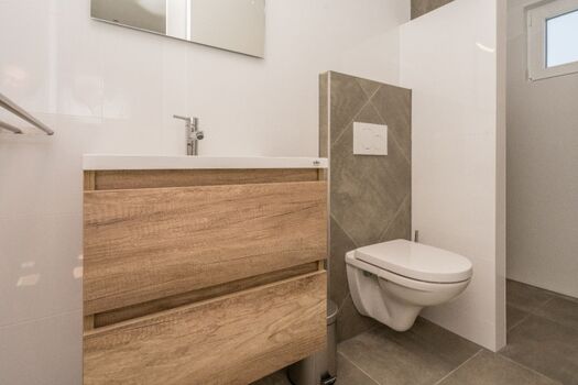 Badezimmer 1 mit Regendusche, Waschbecken und Toilette