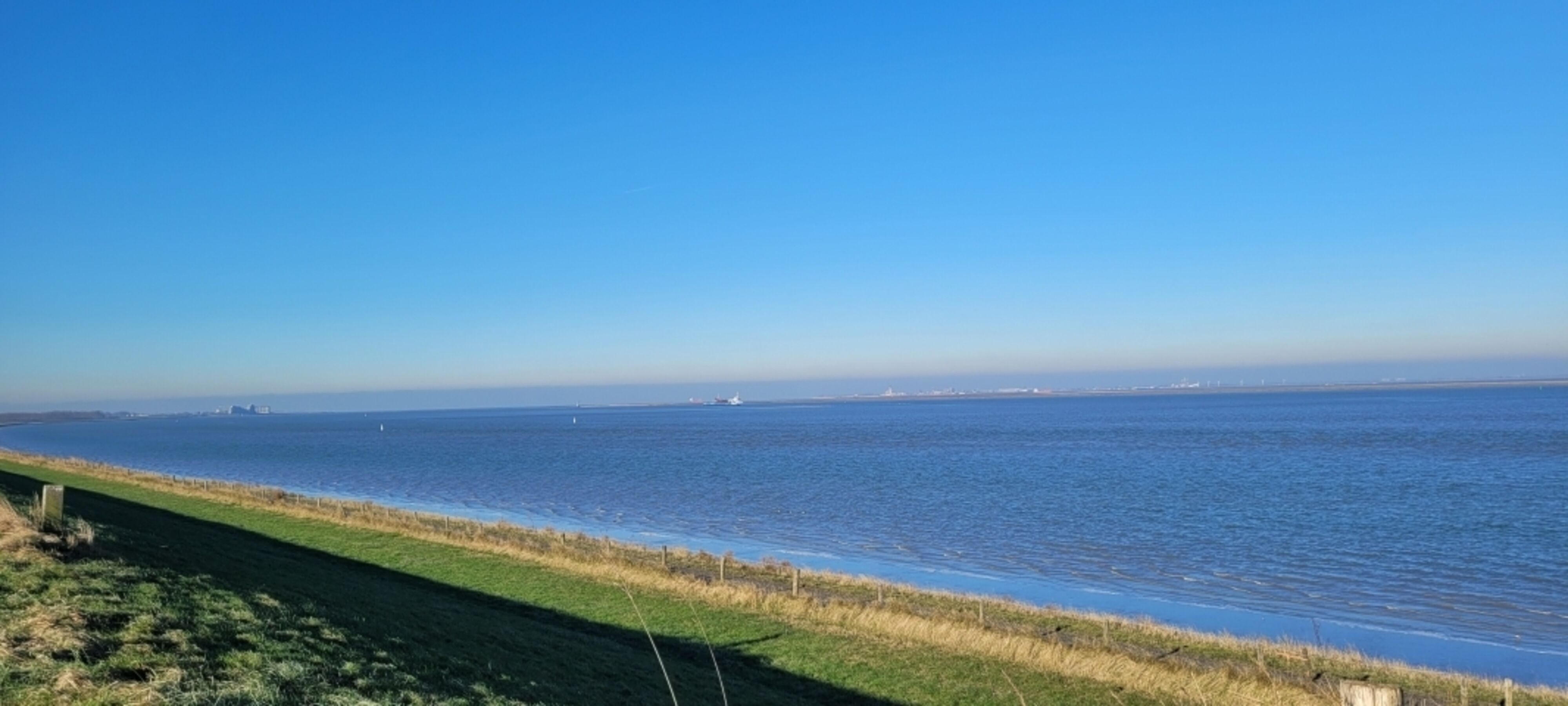 Blick vom Deich auf Meer und Fahrradweg
