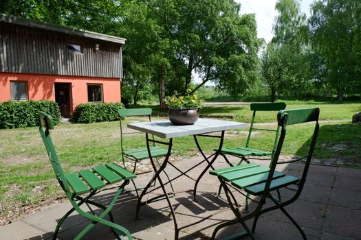 Terrasse vor der Haustür mit Blick auf das Spielhaus und in den großen Garten