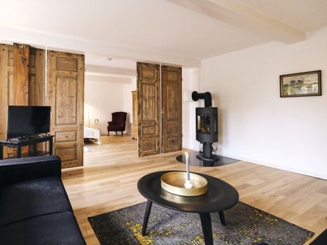 Wohnzimmer mit Kaminofen und TV angrenzend an das Schlafzimmer