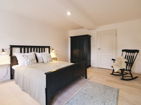 Schlafzimmer mit Ruhesessel und Kleiderschrank