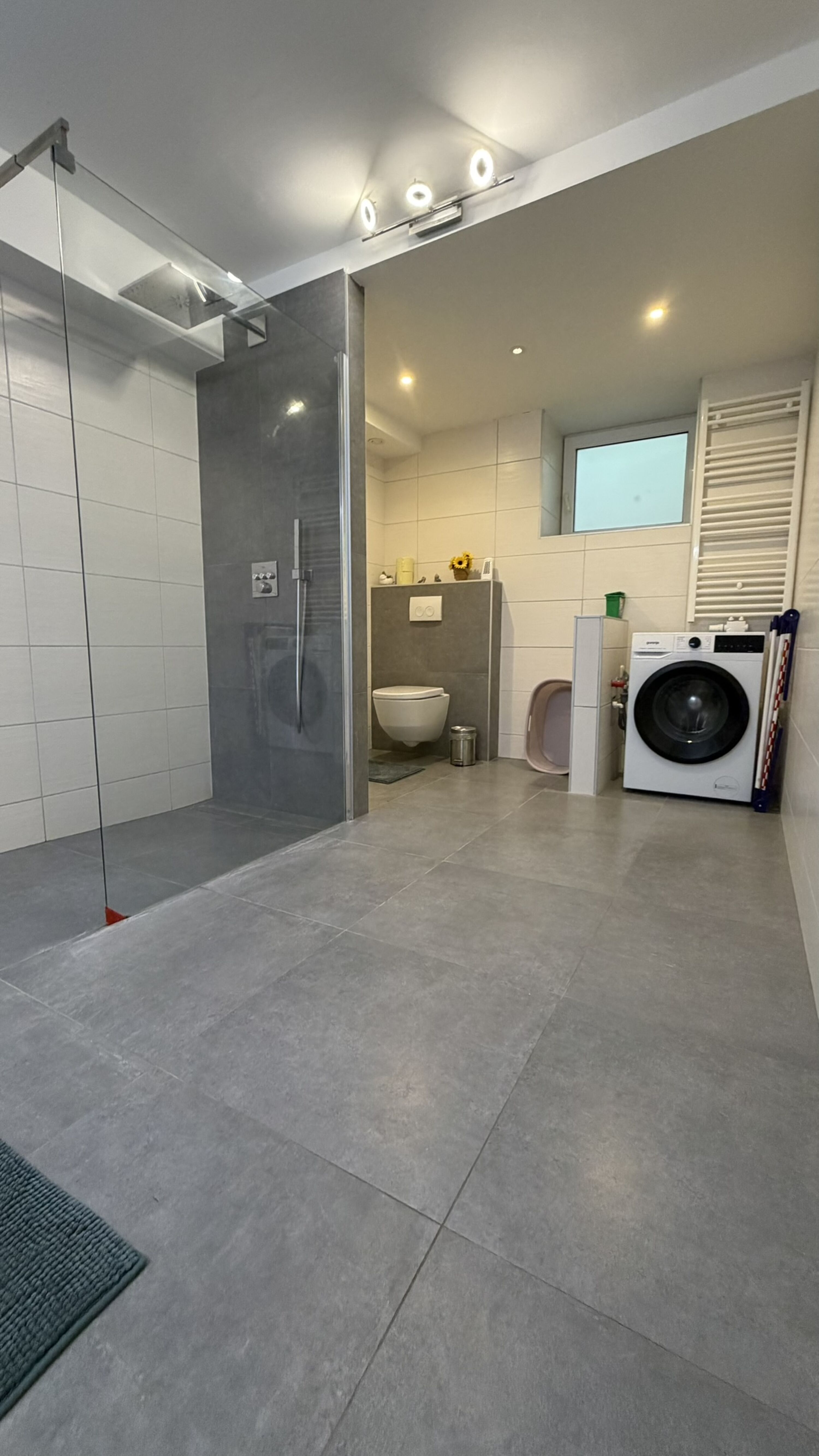 Bad 1 mit Barrierefreier großer Dusche, Doppel Waschbecken, Toilette und Waschmaschine.