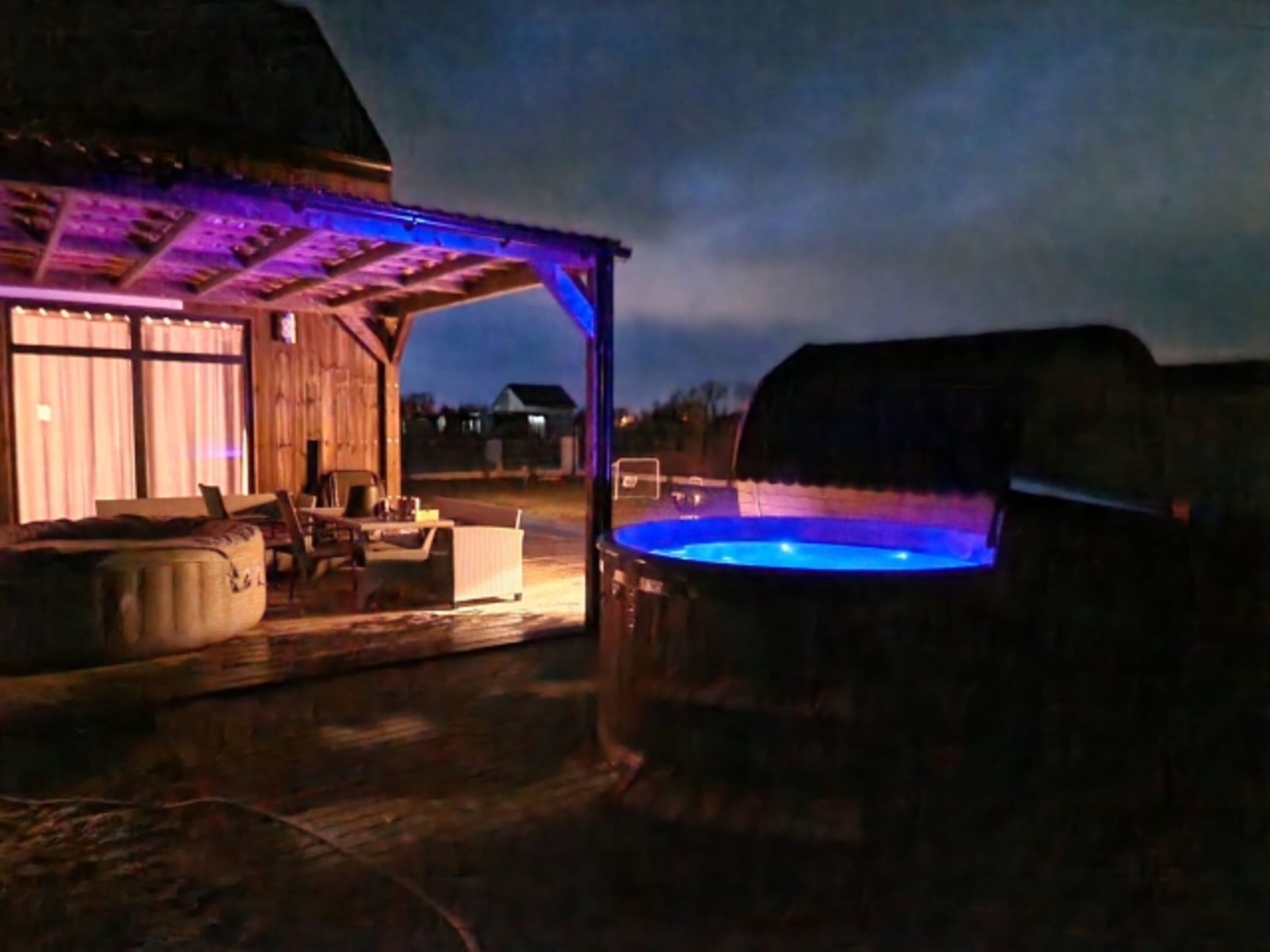 Stimmungsvolle Abendstunden: Beleuchteter Jacuzzi und überdachte Terrasse für perfekte Entspannung nach Sonnenuntergang.