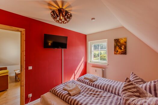 Schlafzimmer mit großem Doppelbett und Blick zum Hochwald