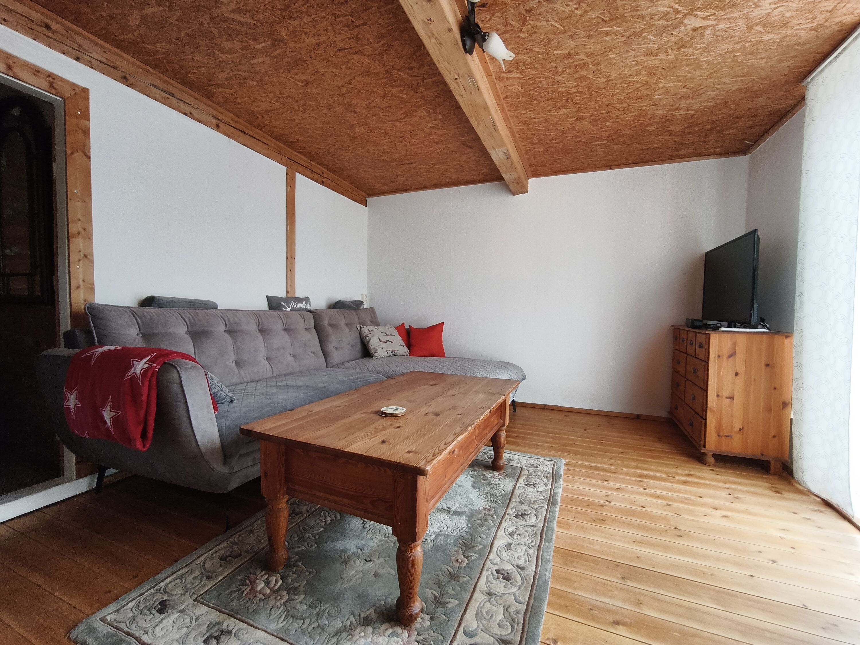 Blick ins Wohnzimmer, welches auf einer Seite eine gemütliche Couch bietet...