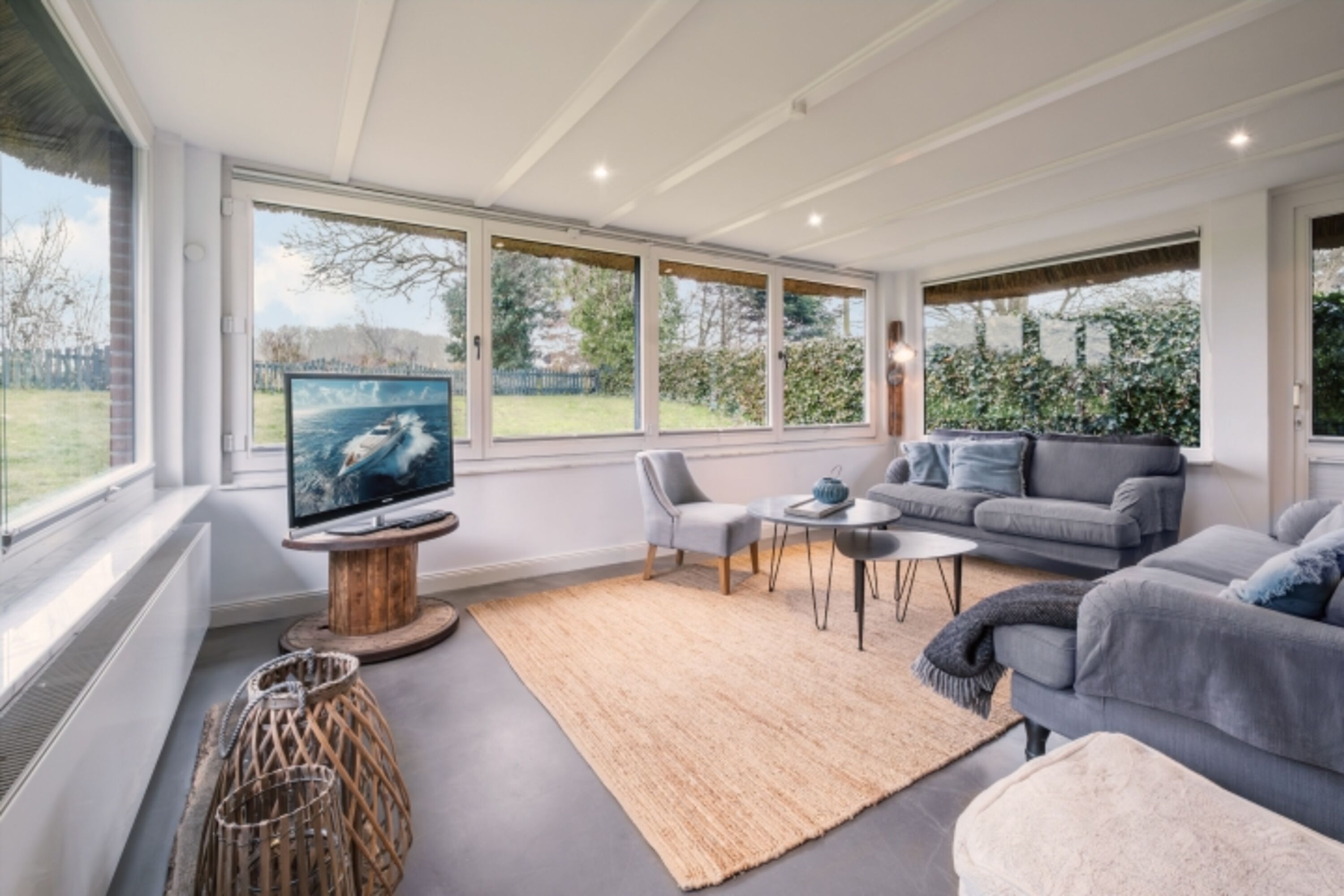 Heller Wintergarten als Wohnzimmer mit TV und Gartenblick