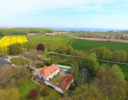 Der Gutshof Freienwillen mit der Flensburger Förde im Hintergrund