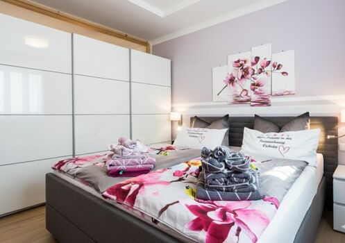 „Schlafkomfort auf höchstem Niveau: Das großzügige Hauptschlafzimmer mit elektrisch verstellbarem Boxspringbett und XXL-Schwebetürenschrank für Ihr gesamtes Urlaubsgepäck.“