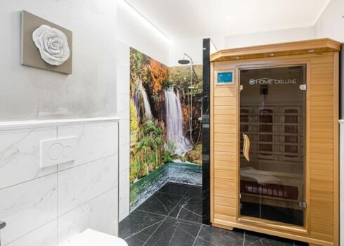 „Ihre private Wellness-Oase: Entspannen Sie in der eigenen Infrarotsauna oder genießen Sie eine belebende Erfrischung unter der großzügigen Regendusche.“
