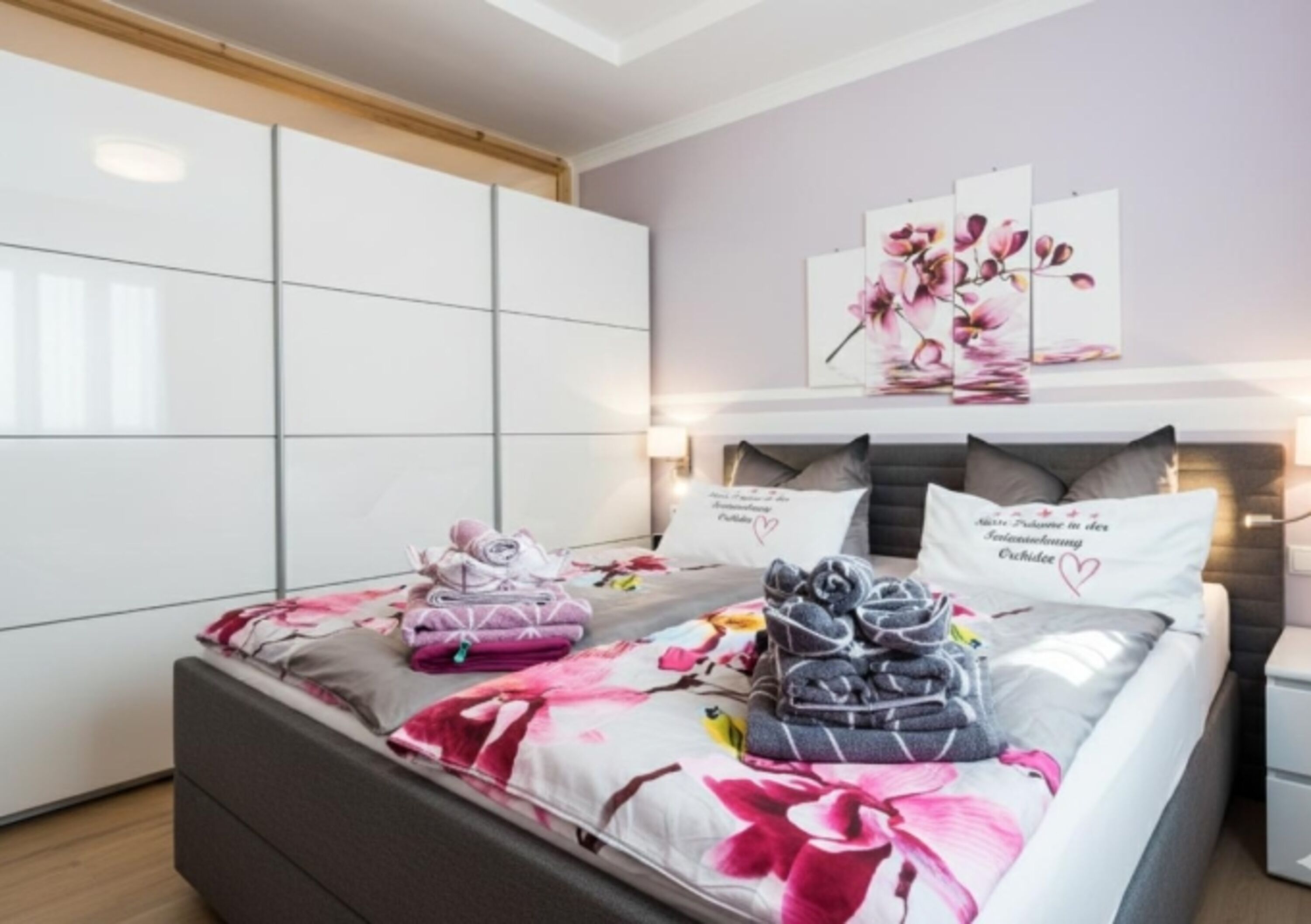 „Schlafkomfort auf höchstem Niveau: Das großzügige Hauptschlafzimmer mit elektrisch verstellbarem Boxspringbett und XXL-Schwebetürenschrank für Ihr gesamtes Urlaubsgepäck.“