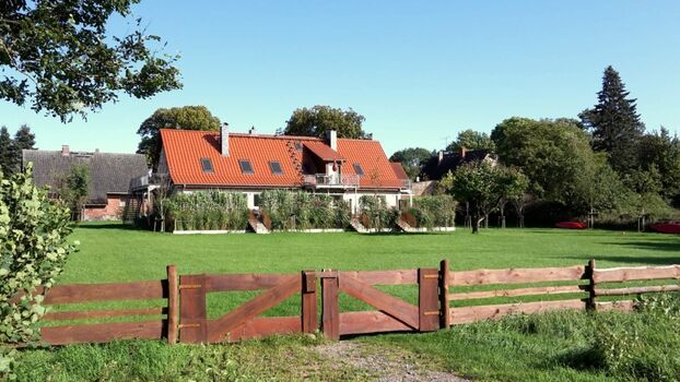 Tante Polly Ferienhof - Blick vom See kommend über die große Wiese zum Ferienhaus